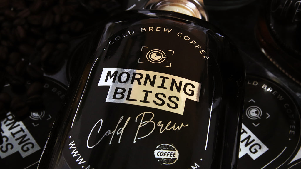 Ovales, spiegelndes silbernes Etikett mit „Morning Bliss“-Design, das auf einer Glasflasche mit kalt gebrühtem Kaffee angebracht ist