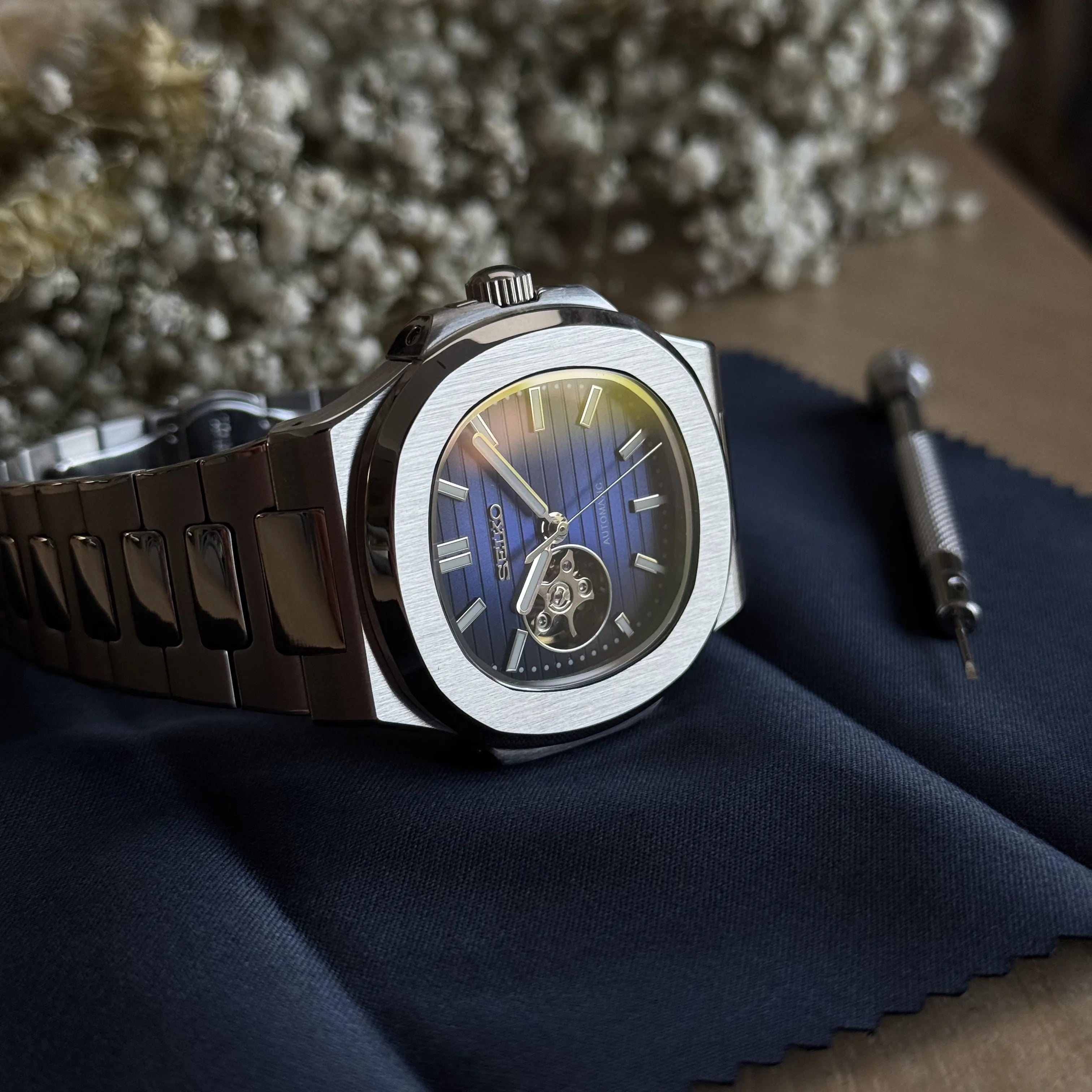 Montre automatique Seiko Mod style Nautilus posée sur un chiffon de nettoyage avec outils d'entretien