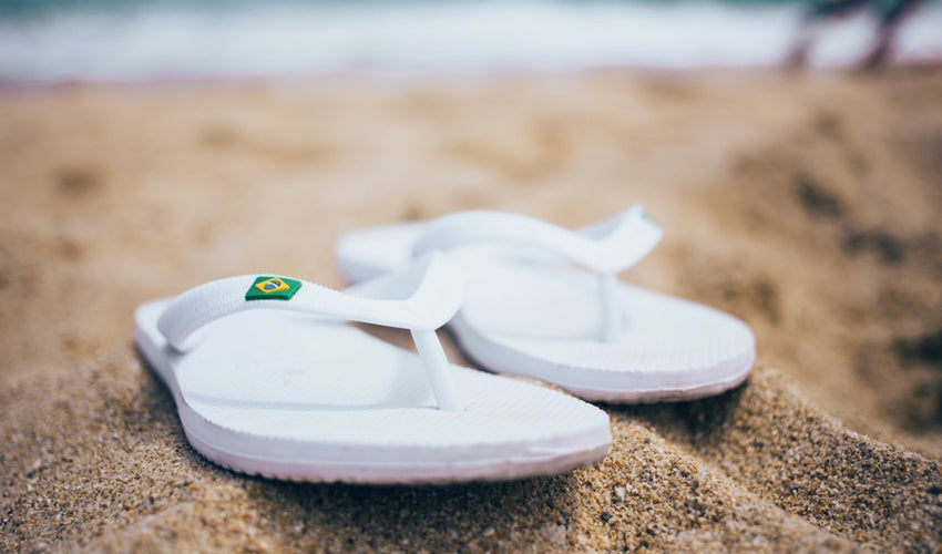 Close up shot of a pair of white flip-flops on beach sand