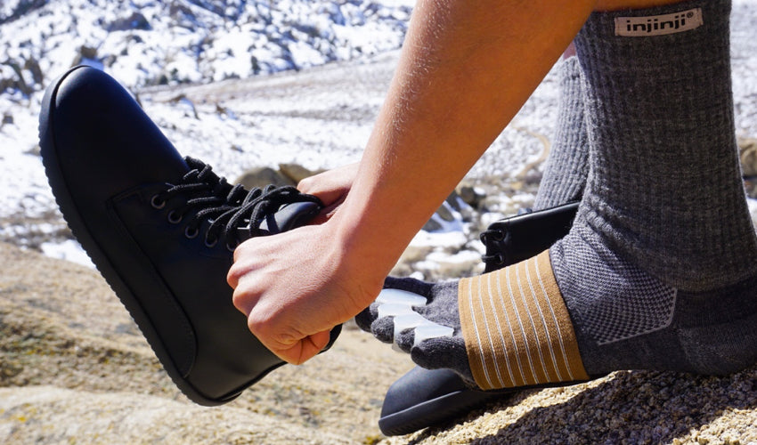 Hiker wearing a full suite of natural footgear, including foot-healthy boots, toe spacers, toe socks, and metatarsal pads