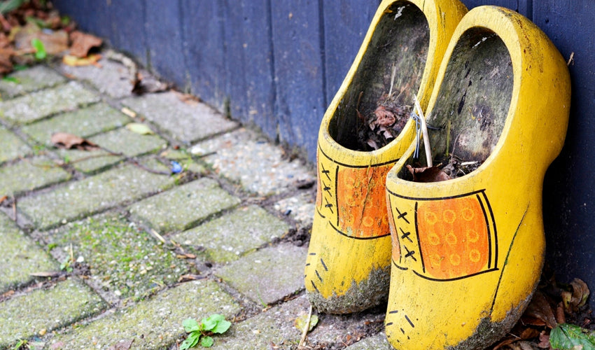 A pair of decorative yellow wooden clogs leaned up against a wood wall