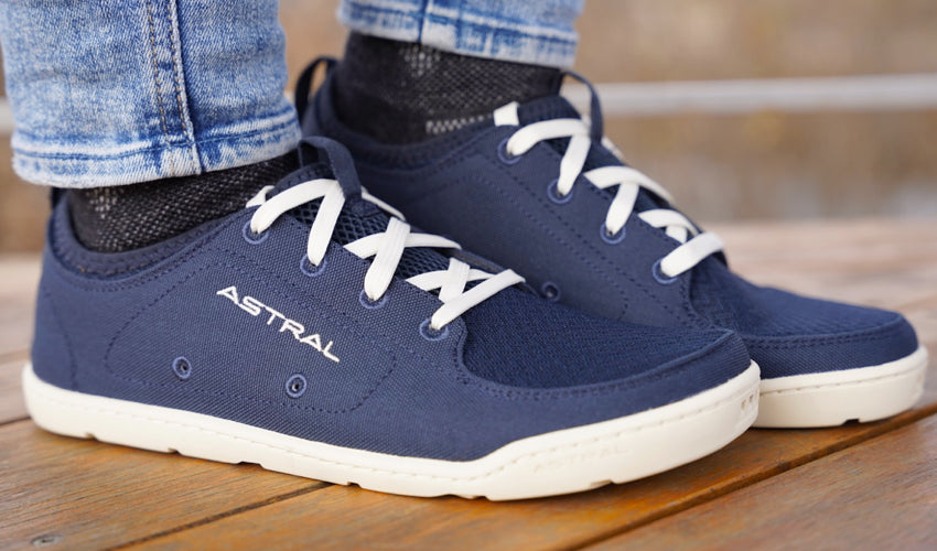 Side view of a pair of Astral Loyak Navy/White shoes with one heel elevated