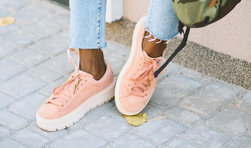 Woman wearing peach-colored conventional shoes with thick soles, heel elevation, and tapering toe boxes