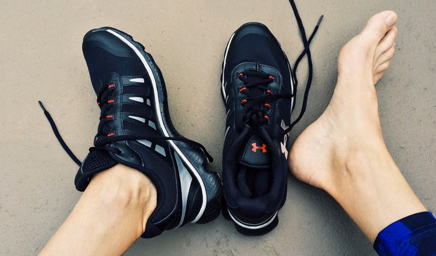 A person sitting on the ground with one shoe on, one shoe off