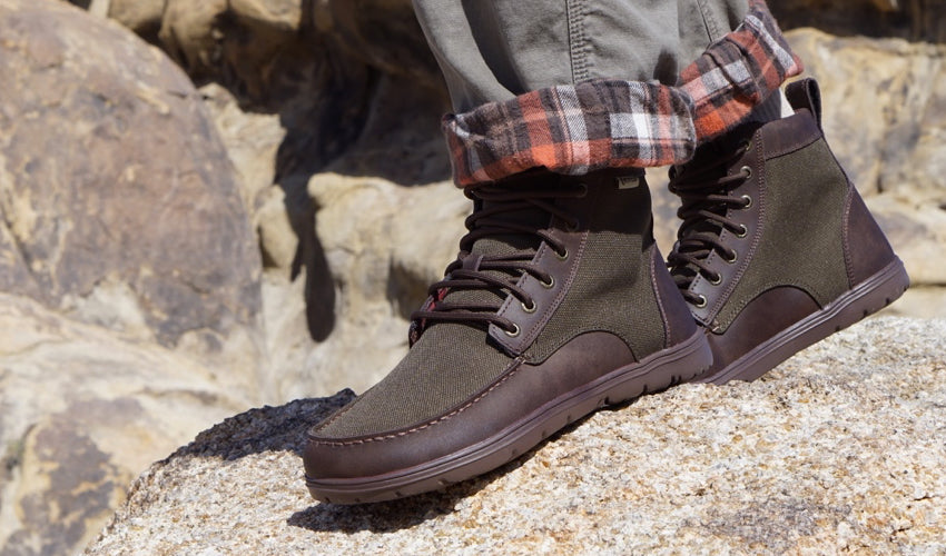 Hiker wearing the Lems Boulder Boot in Nylon Timber striding over rocky ground