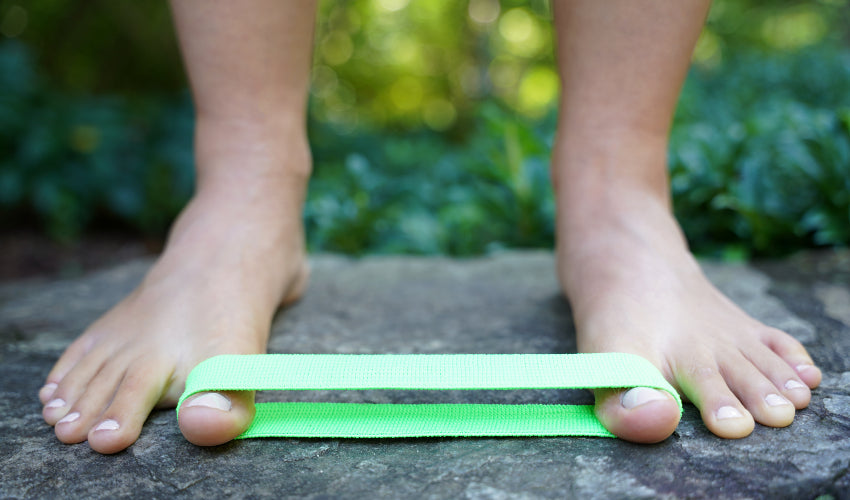 Green BlackBoard Toe Band stretched between two big toes