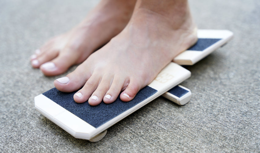 Barefoot person performing an exercise on the BlackBoard Basic foot training platform