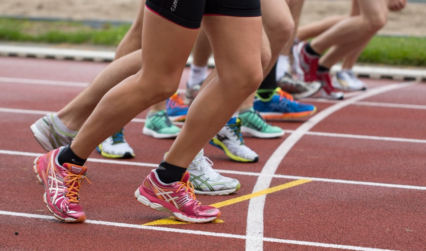 The lower legs of runners in conventional athletic shoes at the start line of a track race