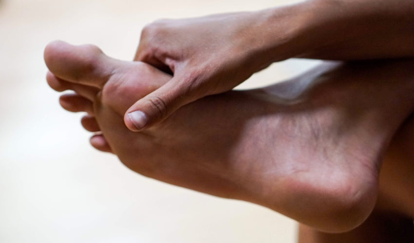 A barefooted person palpating the sole of their foot