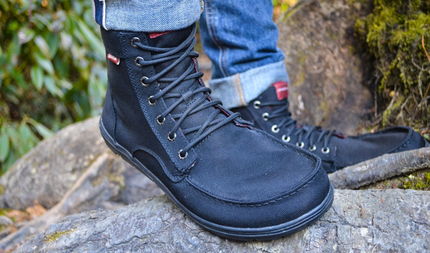 A person wearing Black Lems Boulder Boots in a natural setting