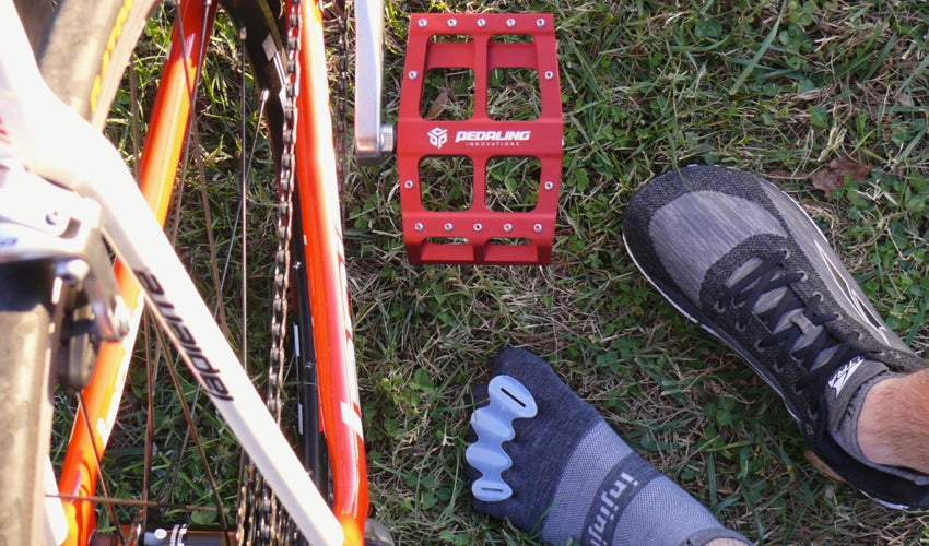 Topdown view of Catalyst Pedals in red along with feet sporting toe spacers, toe socks, and Altra athletic shoes