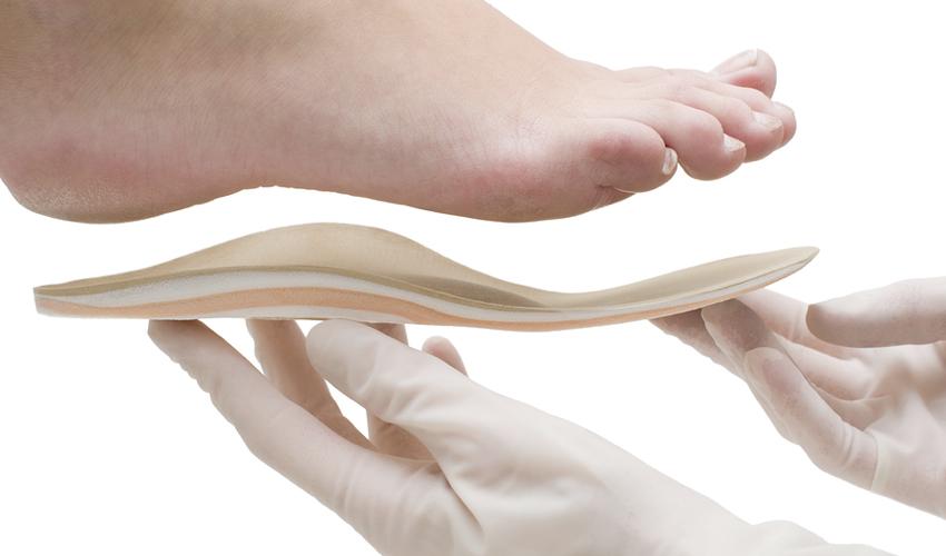 A podiatrist fitting a conventional arch orthotic to a person's sole