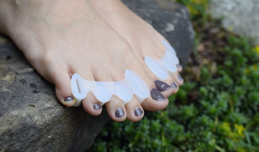 Close-up shot of Correct Toes Original toe spacers on bare feet overhanging a stone step in a garden setting