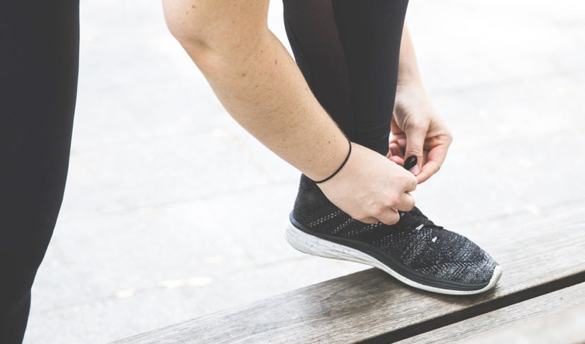 Athlete with a foot up on a bench tying laces of running shoes with heel elevation