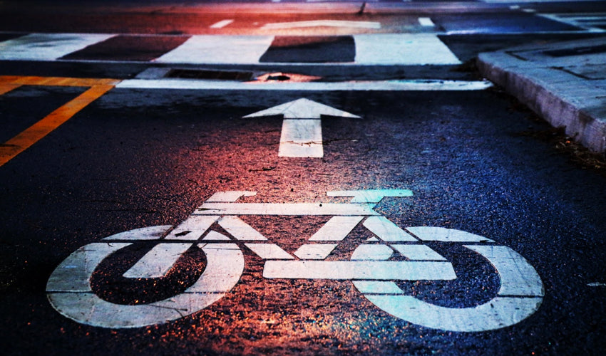 Bike symbol and arrow, in a commuting lane, on damp pavement at dusk