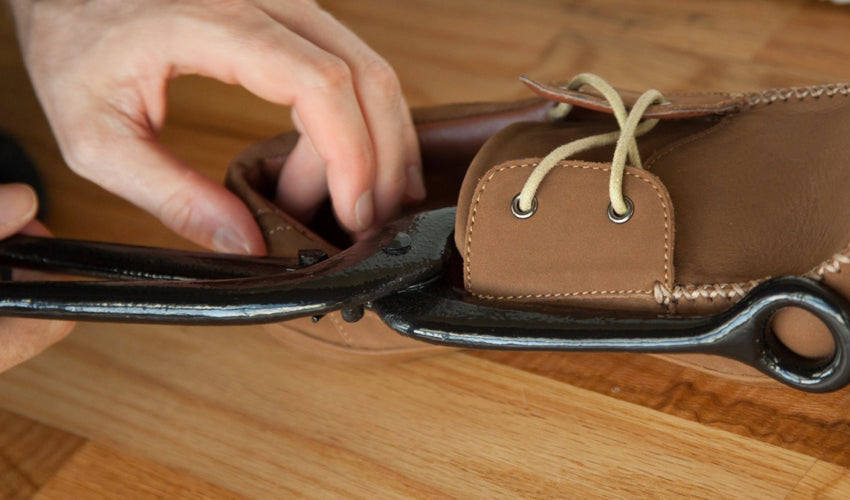 A person using the FootFitter Ball & Ring Shoe Stretcher to create more room in a shoe's toe box