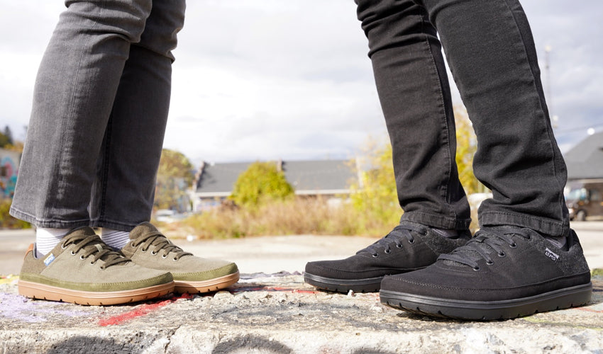 Man and woman wearing Lems Chillum shoes and facing each other on a large concrete block that is covered in graffiti