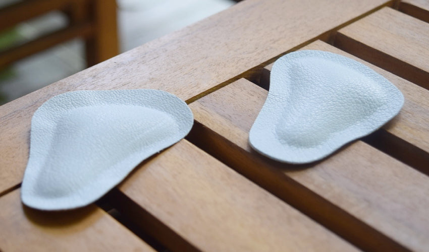 A pair of Pedag metatarsal pads lying on top of a slatted wooden coffee table