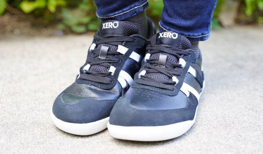 Front-diagonal view of a standing person wearing a pair of Xero Kelso Black/White shoes