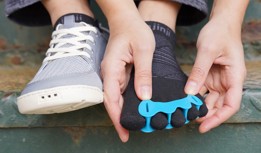 An Astral Loyak shoe-wearer donning a Correct Toes Aqua toe spacer over Injinji toe socks