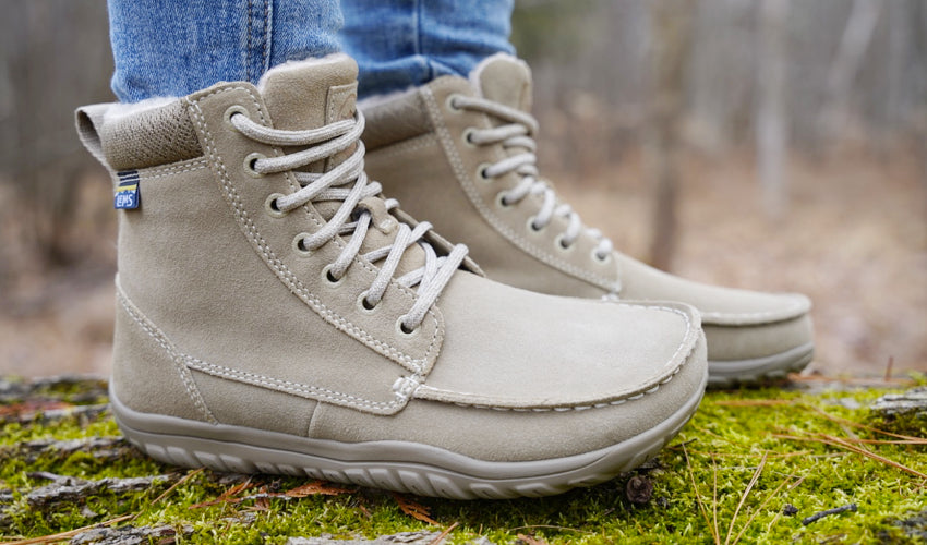 Side view of a person wearing Lems Telluride Boots and standing on a mossy log