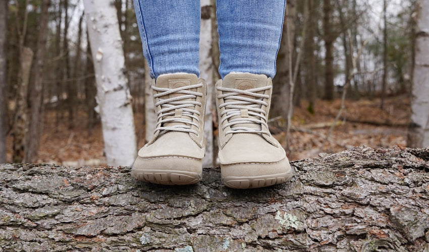 Head-on view of a person wearing Lems Telluride Boots and standing on top of a log