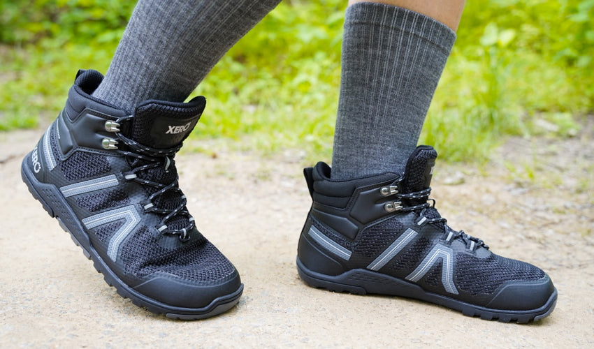 The feet of a hiker striding in a pair of Xero Xcursion Fusion Black Titanium boots