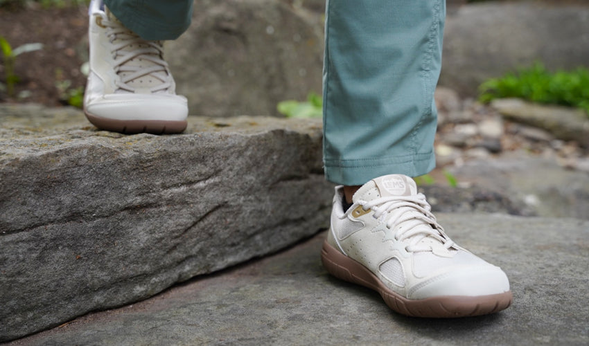 The feet and lower legs of a person wearing Lems Primal Eco minimalist shoes descending a stone staircase