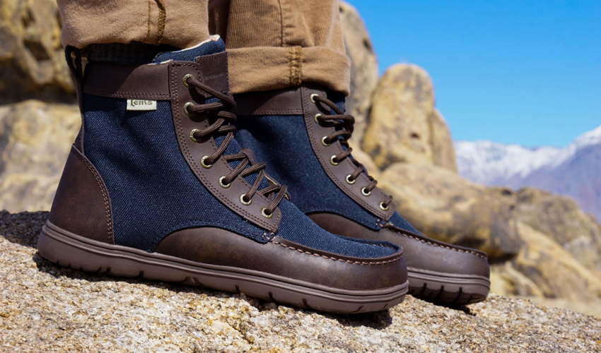 Side view of a pair of Lems Boulder Boots in Navy Stout worn by a hiker in the mountains
