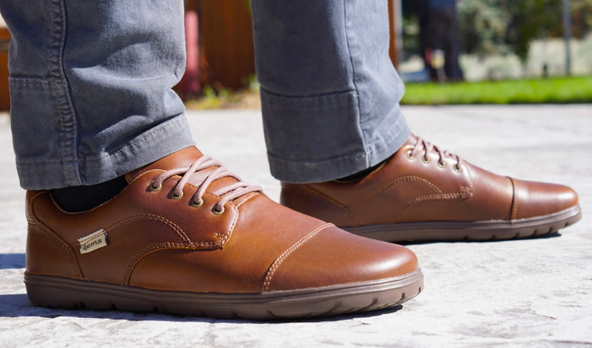 A close-up view of a pair of Lems Nine2five Mocha foot-shaped dress shoes for men