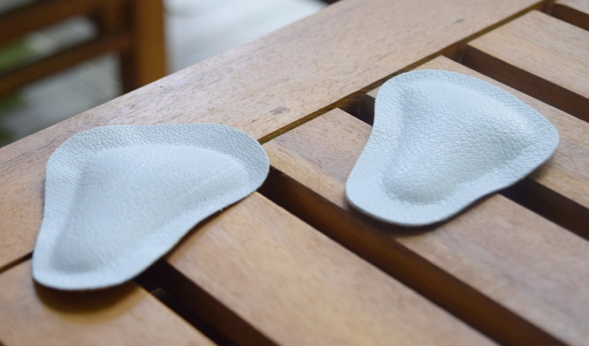 A pair of Pedag metatarsal pads sitting on a slatted wooden coffee table