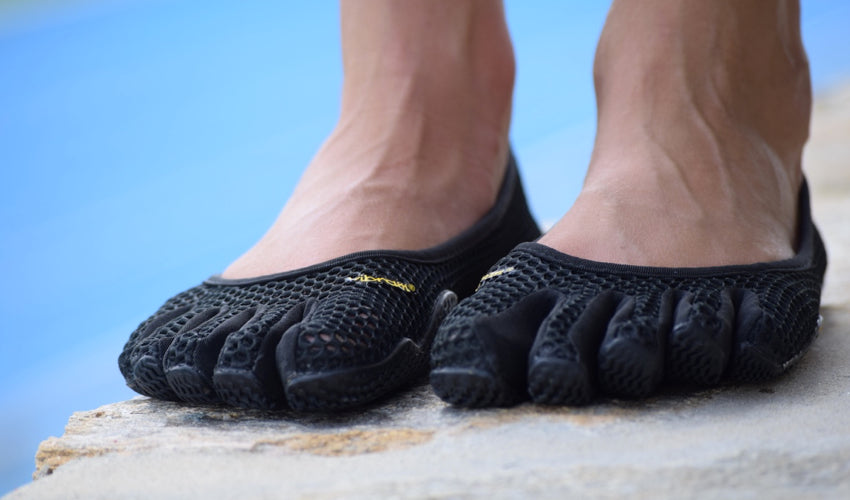 Vibram FiveFingers VI-B shoes on the feet of a person with blue running track in the background