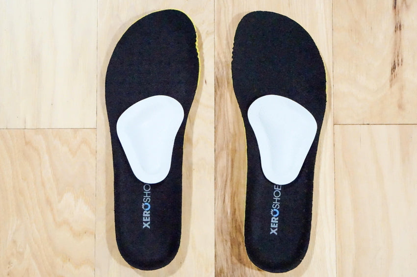 Top down view of a pair of Pedag metatarsal pads mounted on black Xero Shoes insoles