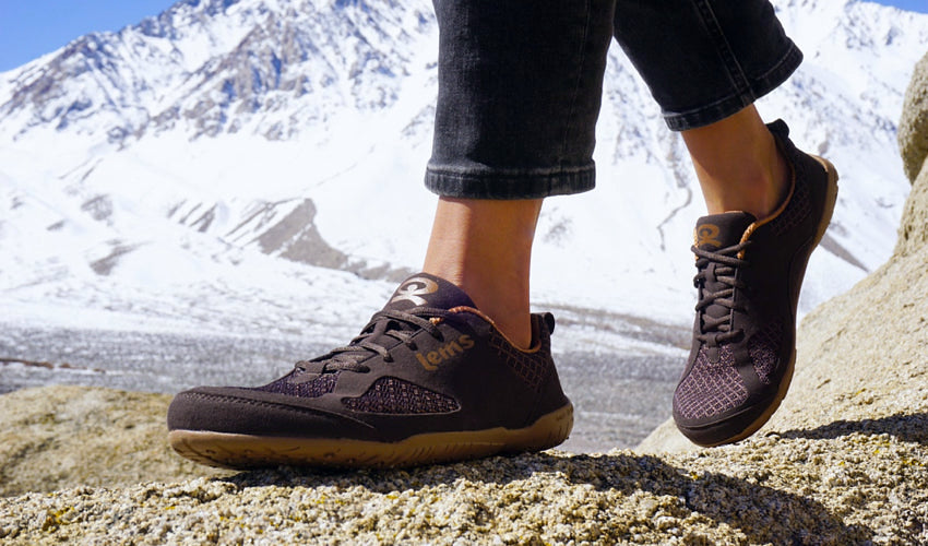 A person walking in Lems Primal 2 Brown shoes with snowy mountains in the background