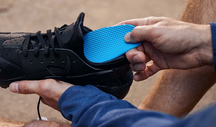 Person inserting a Naboso Activation insole into a black shoe