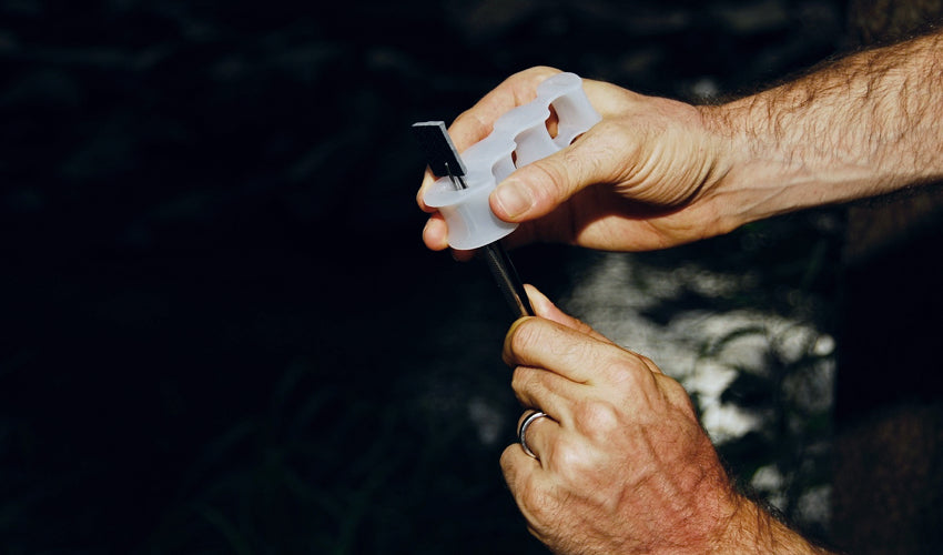 A person using a pair of tweezers to insert a “shim” into one of the cavities of the Correct Toes device