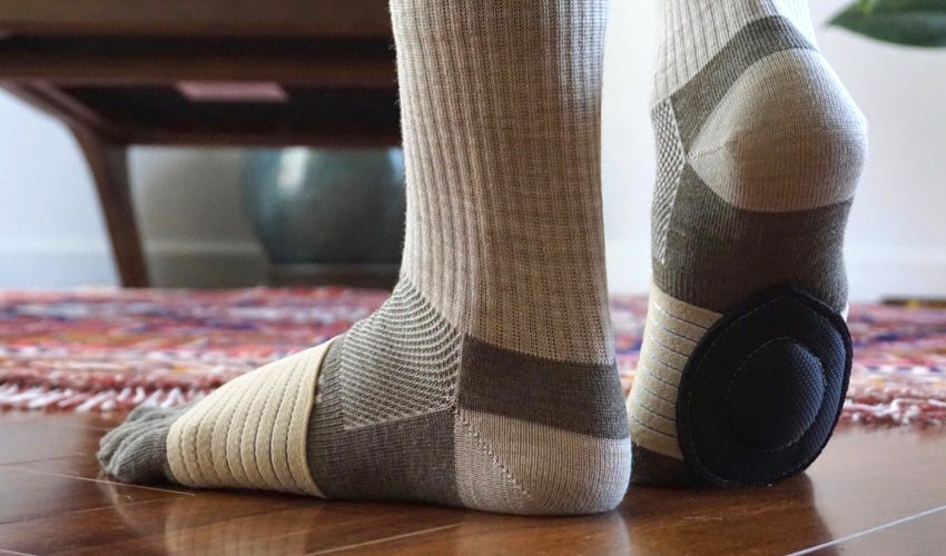 Close-up view of a person in toe socks wearing Strutz Rx foot pads in Beige/Black
