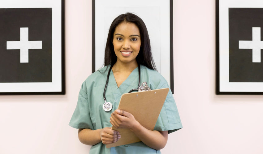 A smiling female physician with a stethoscope around her neck holding a clipboard