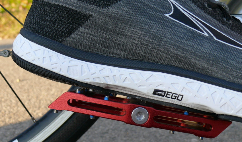 Close-up side view of a Red Catalyst Pedal and an Altra athletic shoe