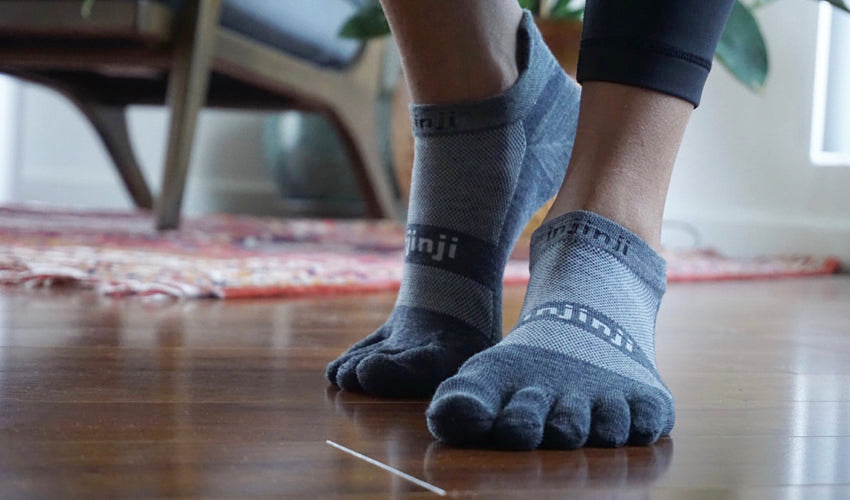 Pair of healthy feet wearing toe socks with a well-aligned big toe helping to enable natural arch support