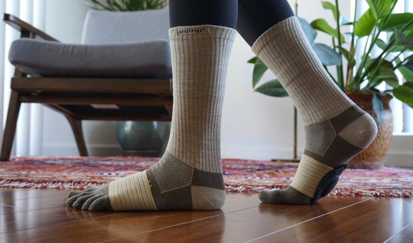 Person walking indoors on wood floors while wearing Injinji toe socks and Strutz foot pads