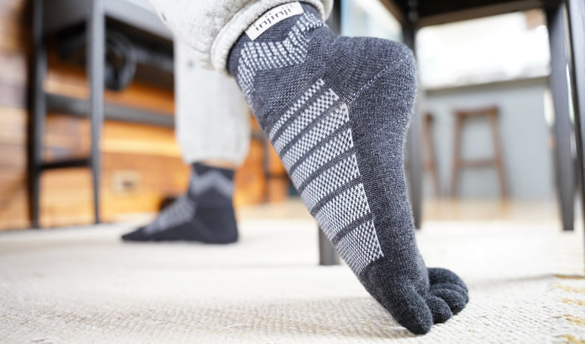 A seated person wearing Injinji toe socks performing the toe extensor stretch