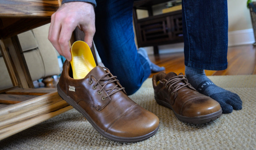 Person putting a Tuli's heel cup into a pair of Lems Nine2five Mocha shoes