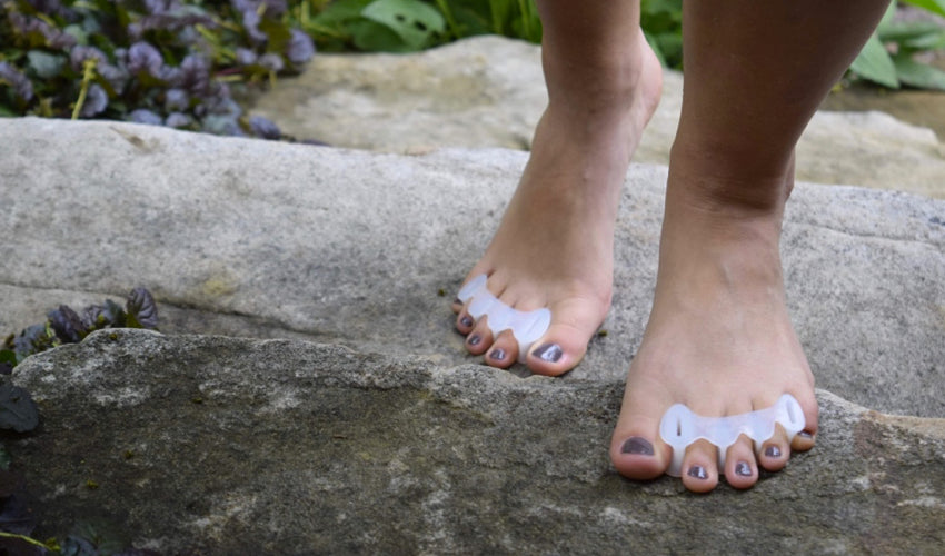 A person wearing Correct Toes Original toe spacers while climbing a set of stone steps