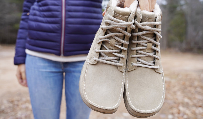 Person holding a pair of Lems Telluride Boots in front of their body at arm's length