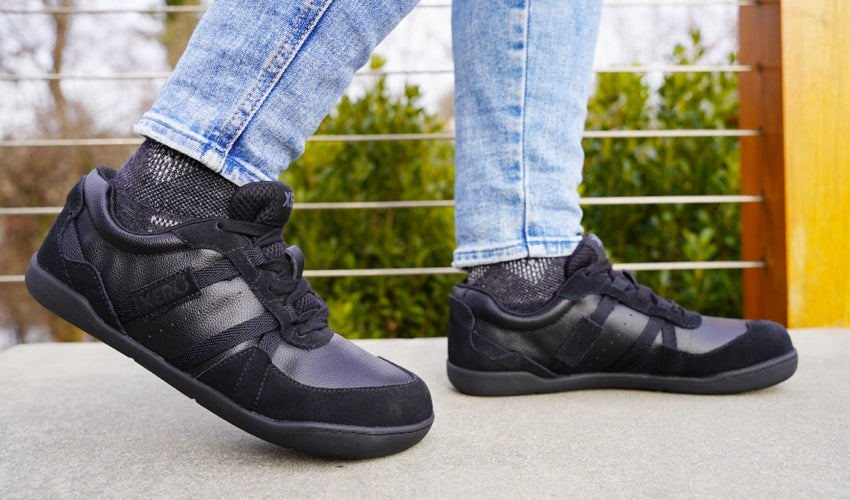 Side view of the feet of a Xero Kelso shoe-wearer striding over a concrete surface