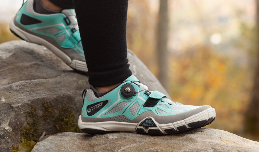 Athlete clambering over rocks in shoes with flexible toe spring