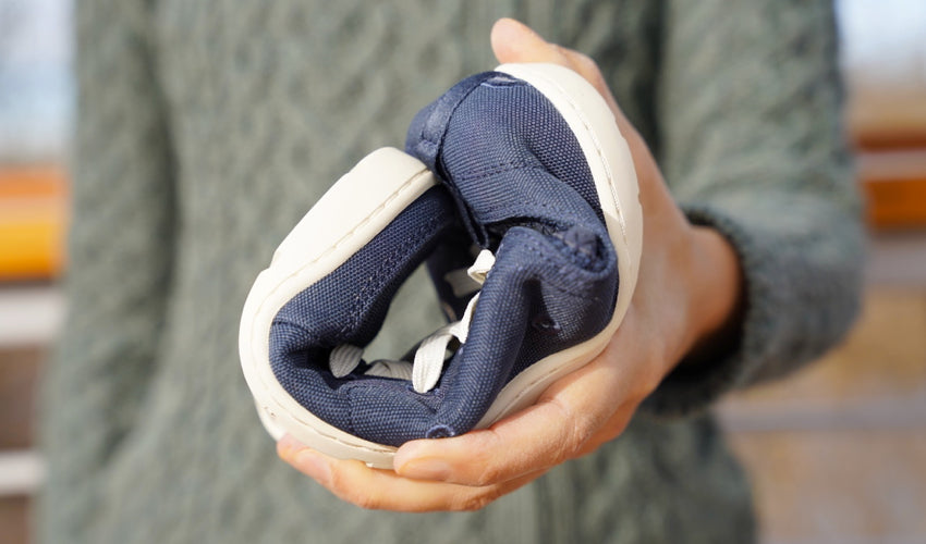 A person holding an Astral Loyak shoe in front of them that's folded into a ball