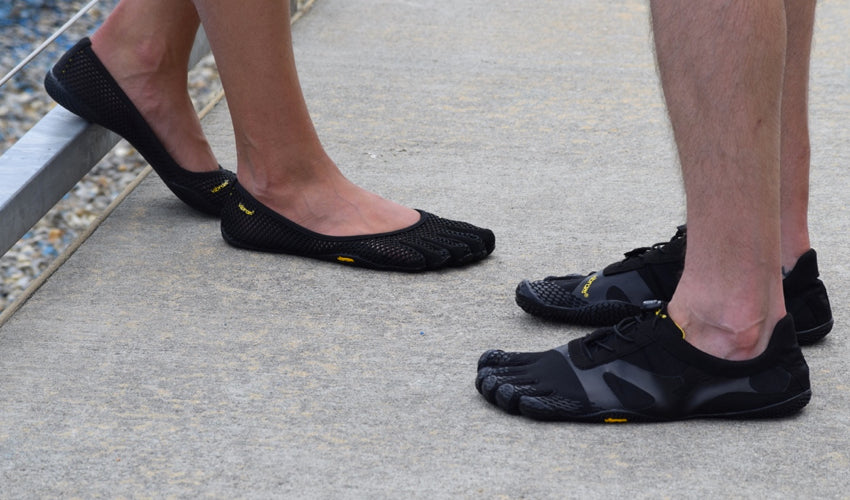 Two people wearing Vibram FiveFingers shoes and standing on a concrete platform