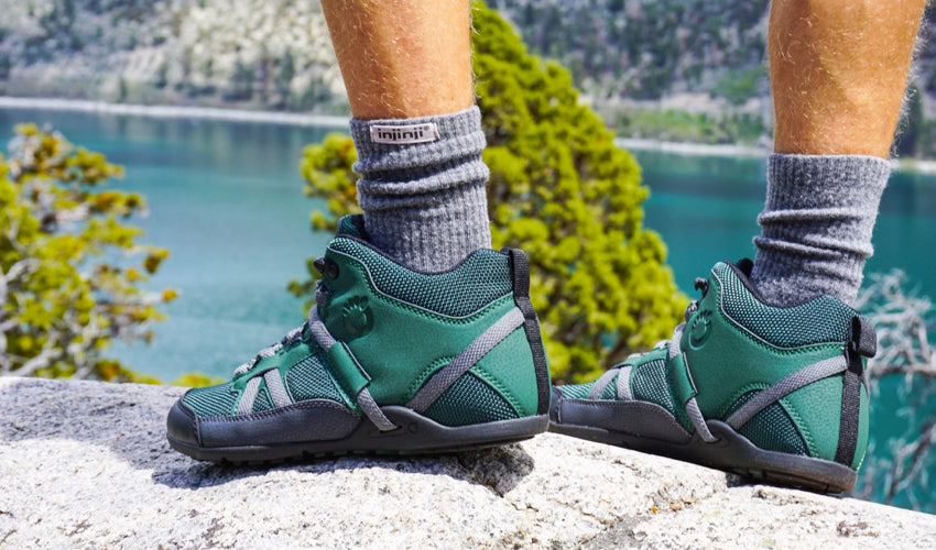 Hiker wearing Xero DayLite Hiker boots and standing on a rock overlooking a lake